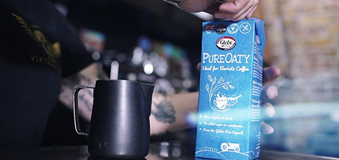 Glebe Farm Pure Oaty milk carton beside a steaming jug